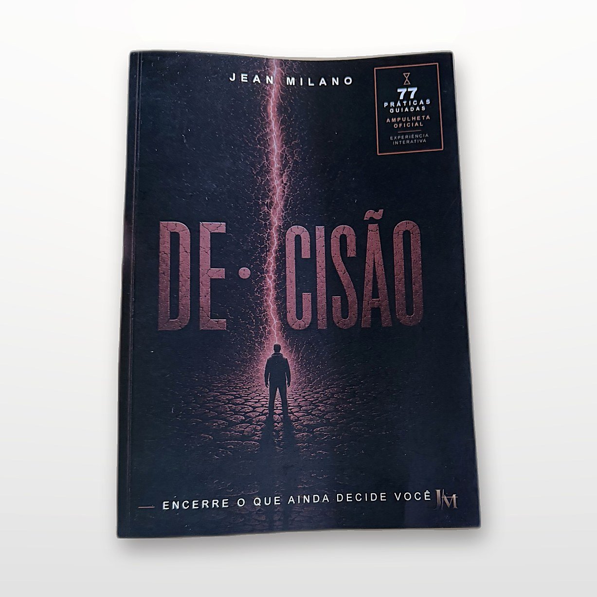 O livro DE·CISÃO segurado na mão, mostrando o tamanho real
